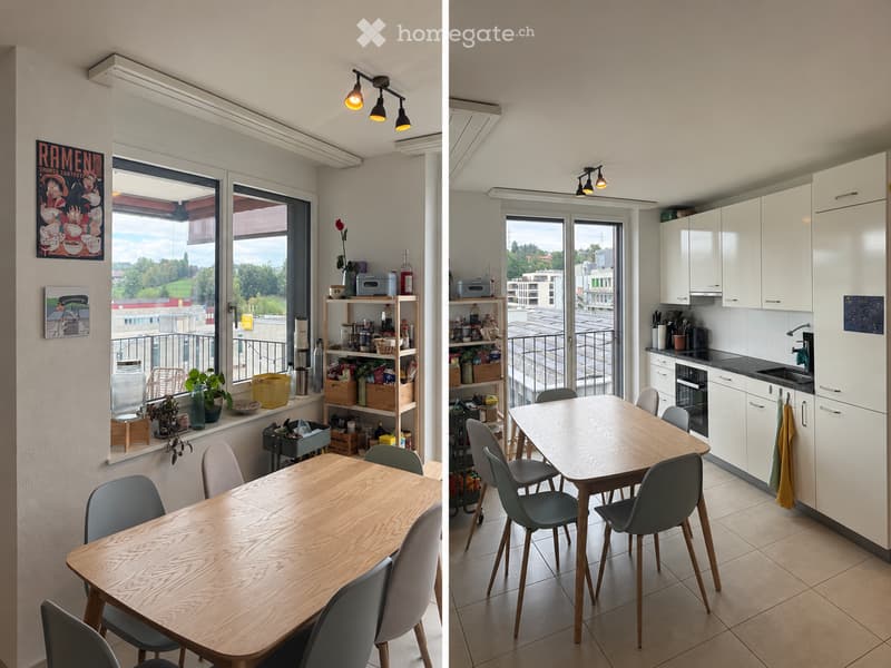 Bright, modern kitchen and dining area with white cabinets, wooden dining table, grey chairs, and a view of the city.