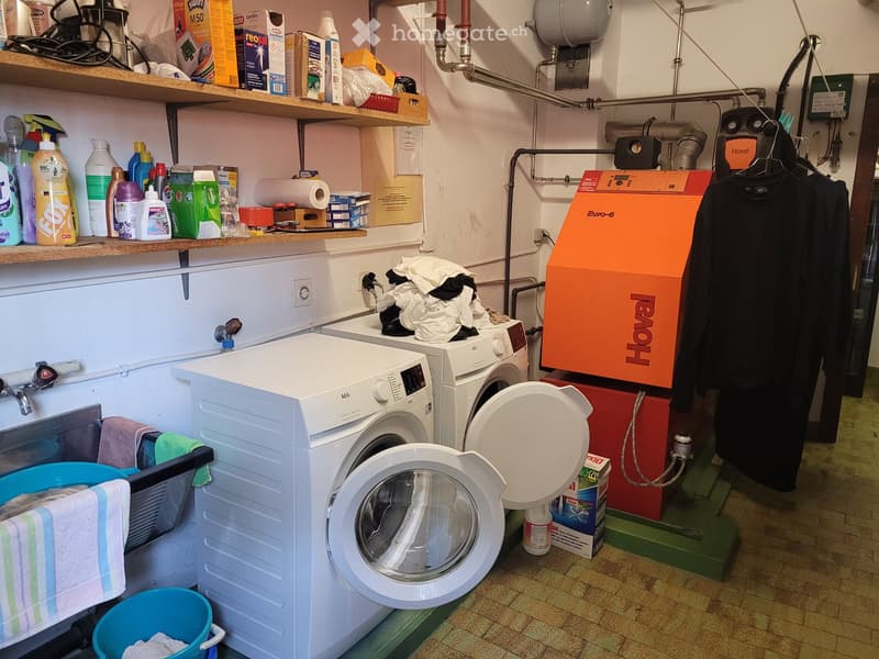 a room with shelves, washing machines, laundry baskets, and cleaning products