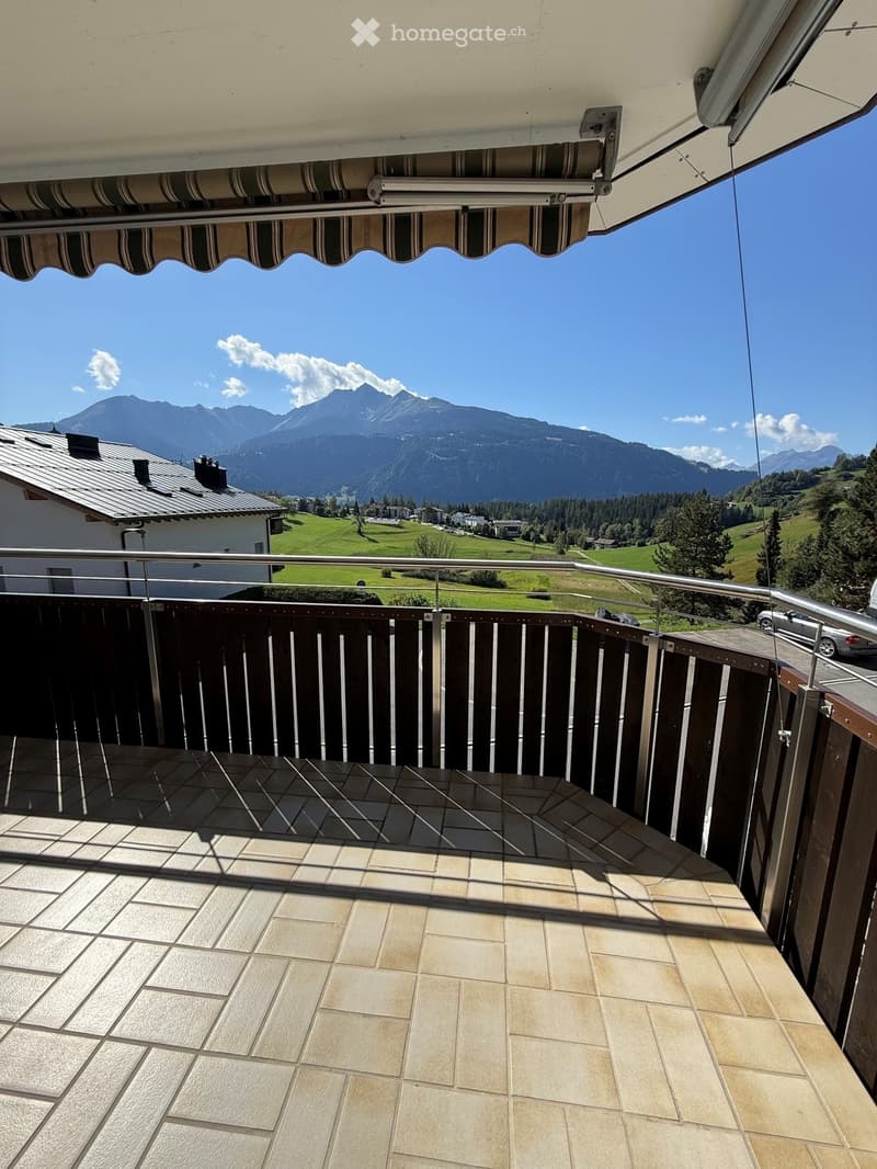 Balcony with tiled floor, wooden railing, and scenic mountain view.