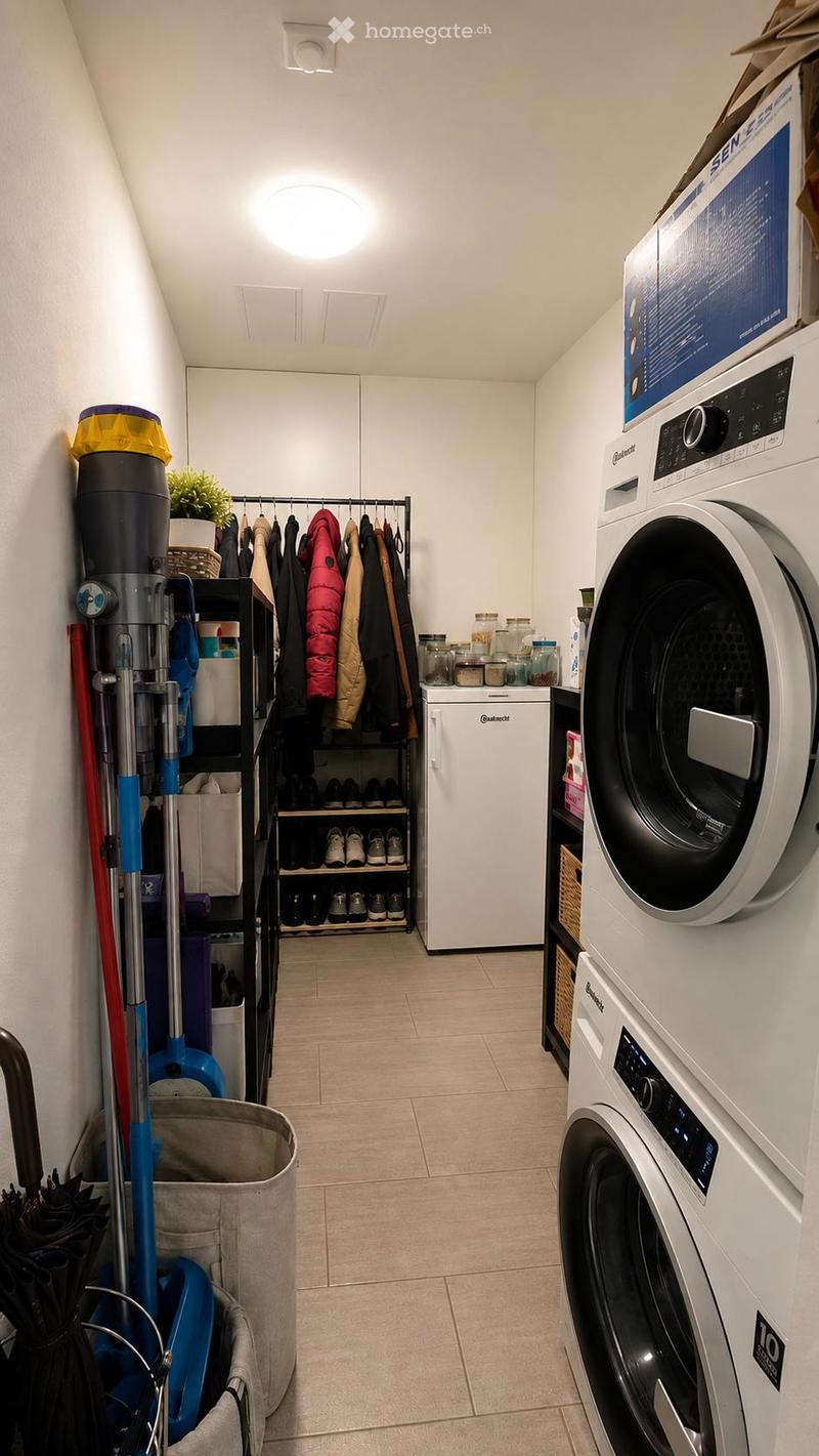 Well-lit laundry room with a washing machine, refrigerator, closet, shoe rack, cleaning supplies, and storage bins.