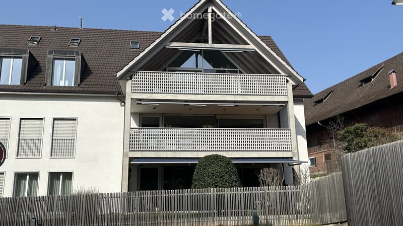 Two-story house with white exterior, multiple balconies, and a well-maintained garden area.