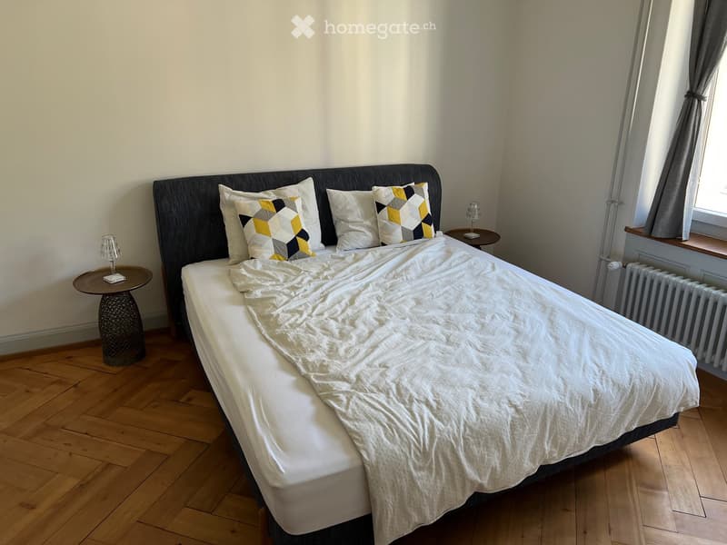 Cozy bedroom with a neatly made bed, two nightstands with table lamps, and patterned pillows.