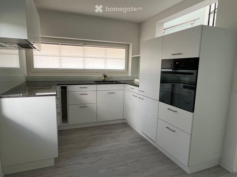 Modern kitchen with white cabinets, stainless steel appliances, and a central island.