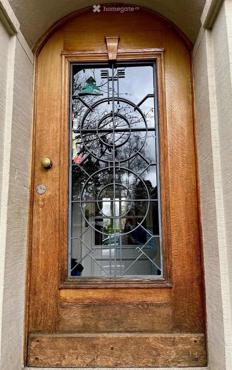 Wooden window with decorative metal grille, glass panes, and a small Christmas tree decoration visible through the glass.