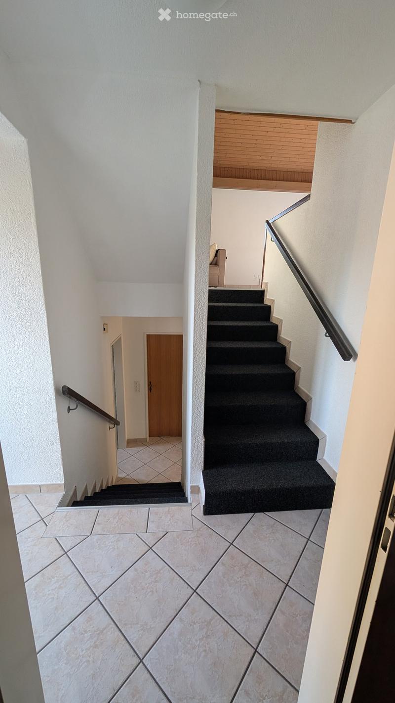 Entrance, double flight of stairs, tiled floor, tiled walls, wooden handrail, wooden door, beige chair
