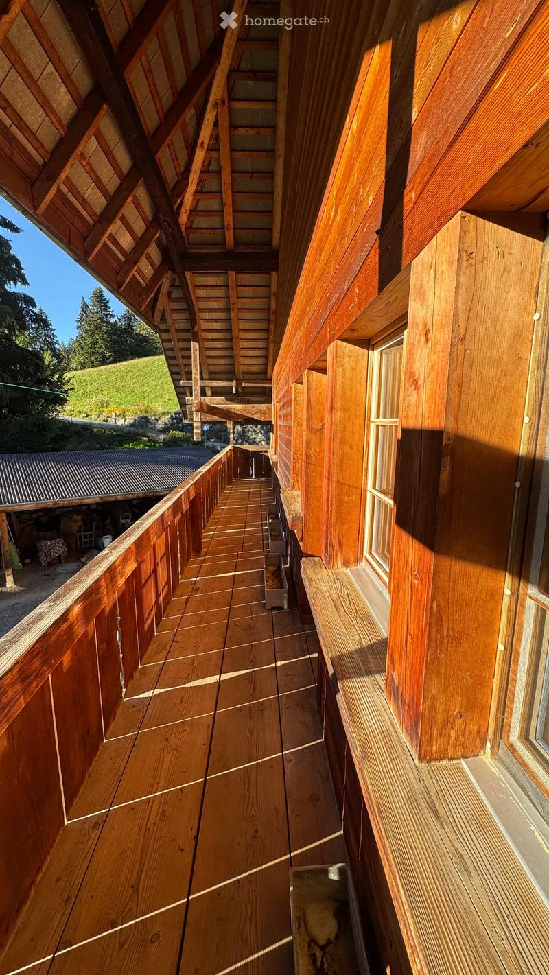 Wooden balcony with wooden railings, wooden decking, and a view of a grassy area and trees.