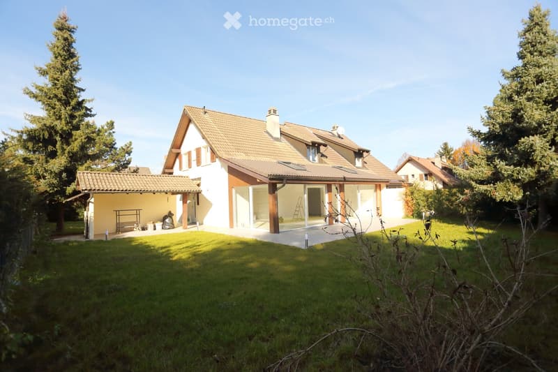 House. Modern house with a brown roof, glass windows, and a patio. Surrounded by a well-maintained lawn and trees.