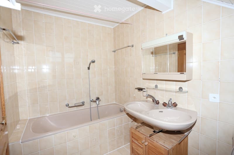 Bathroom. Bathroom with beige tiles, bathtub, double sink, mirror, and wooden cabinet.