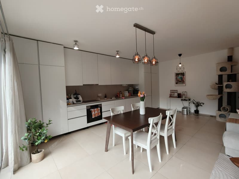 Modern kitchen and dining area with white cabinets, a dark wooden dining table, white chairs, and a cat tree in the corner.