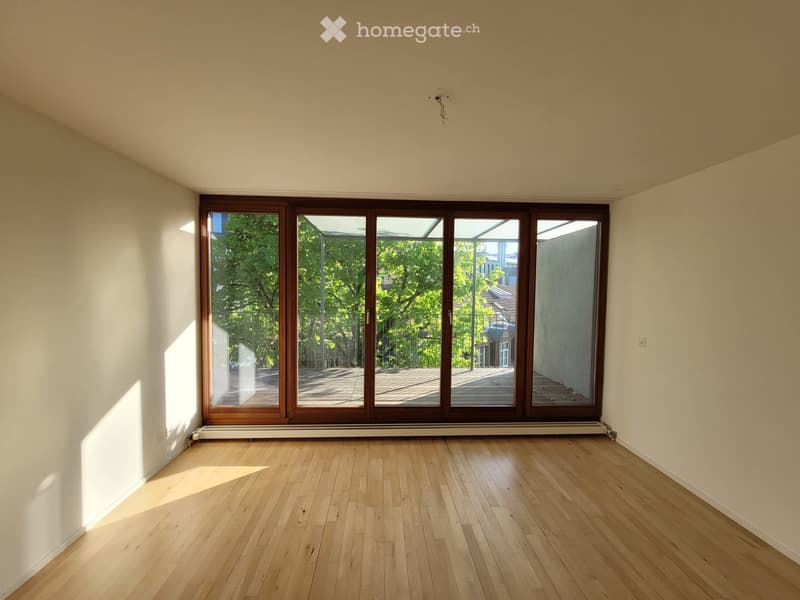 Empty room with wooden flooring and large sliding glass doors leading to a balcony or outdoor area.