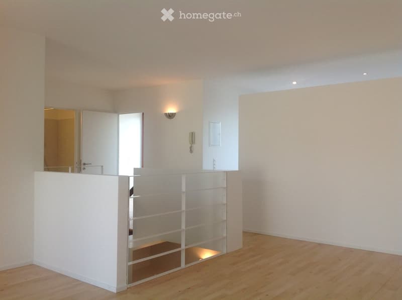 Empty room with light-colored walls, wooden flooring, and a glass partition. No furniture or equipment is present.