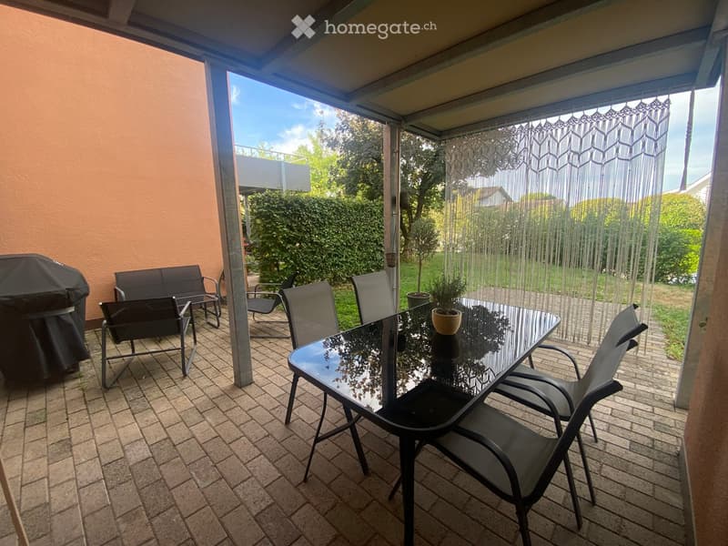 Covered patio with tiled floor, glass table, chairs, bench, and covered grill.