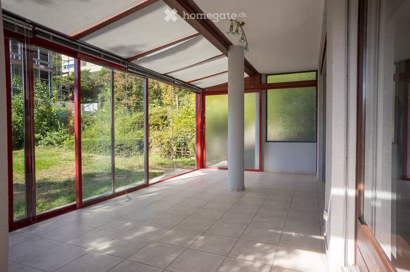Empty room with tiled floor, large glass windows, and a central column. No furniture or equipment present.