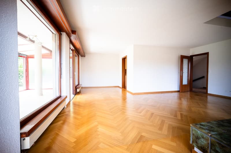 Empty room with wooden flooring, large windows, and white walls. No furniture or equipment present.
