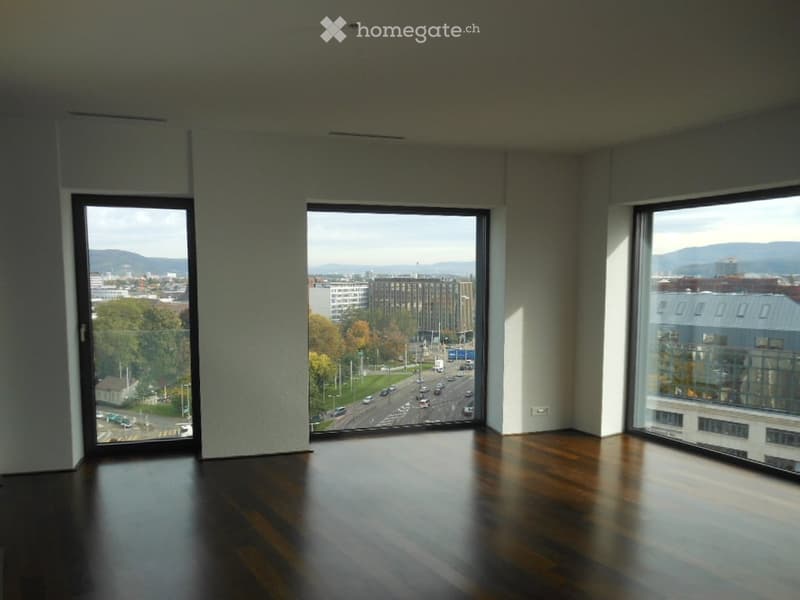 Empty room with wooden flooring and large windows offering a cityscape view.