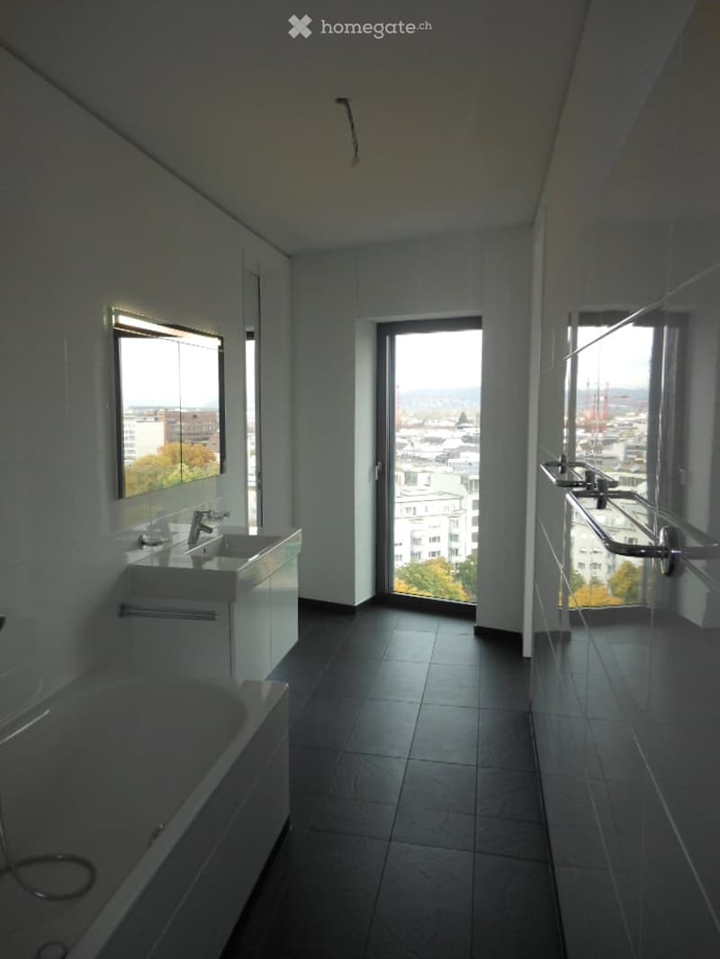 Modern bathroom with dark tiled floor, white walls, a sink with a faucet, a bathtub, and a large window offering a city view.