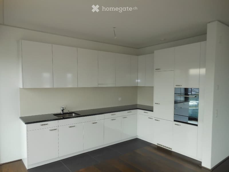 Modern kitchen with white cabinets, black countertops, and a stainless steel sink and oven.