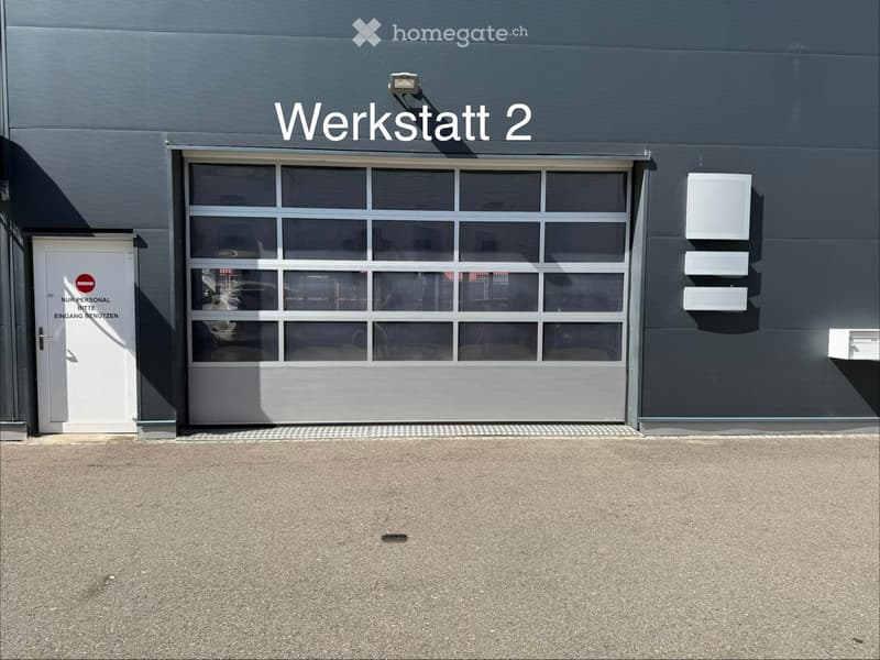 Exterior view of a building labeled "Werkstatt 2" with a large garage door and a side entrance marked for staff only.