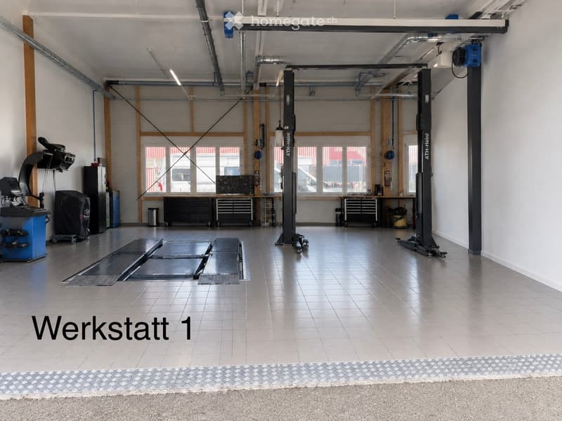 Workshop with tiled floor, large windows, tool cabinets, a workshop lift, and a diagnostic machine.