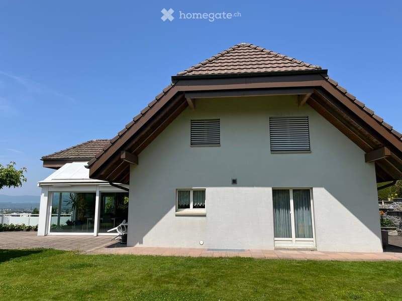 House. Single-story house with a tiled roof, white exterior, large windows, and a well-maintained lawn.