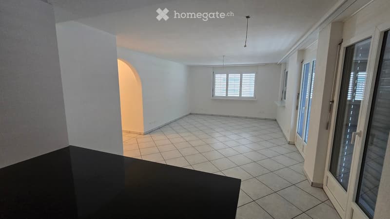 Empty room with tiled floor, white walls, large windows, and a sliding glass door leading to a balcony.