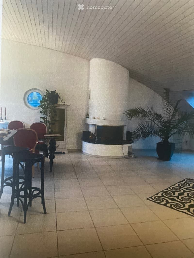 Dining area with a round table, four stool chairs, a fireplace, and potted plants.