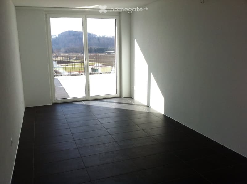 Empty room with dark tiled floor and large sliding glass door leading to outdoor area.