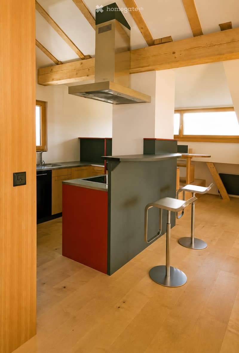 Modern kitchen with a central island, two stools, and built-in appliances including a sink, faucet, and dishwasher.