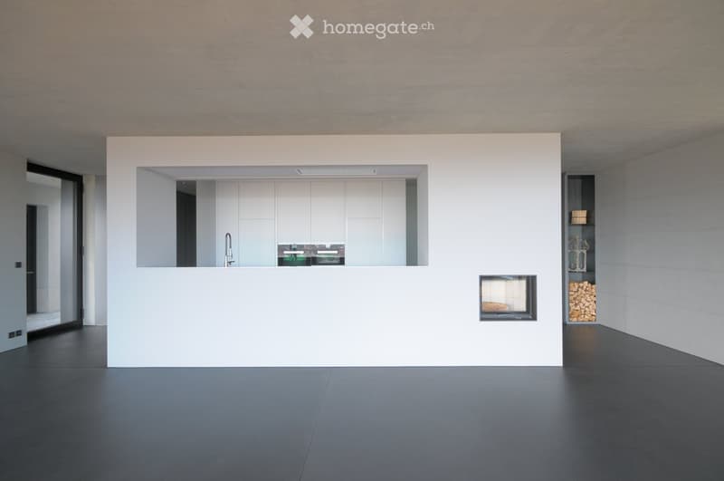 Modern, minimalist room with a sleek white cabinet, a built-in sink with a faucet, and a fireplace with a stack of firewood nearby.