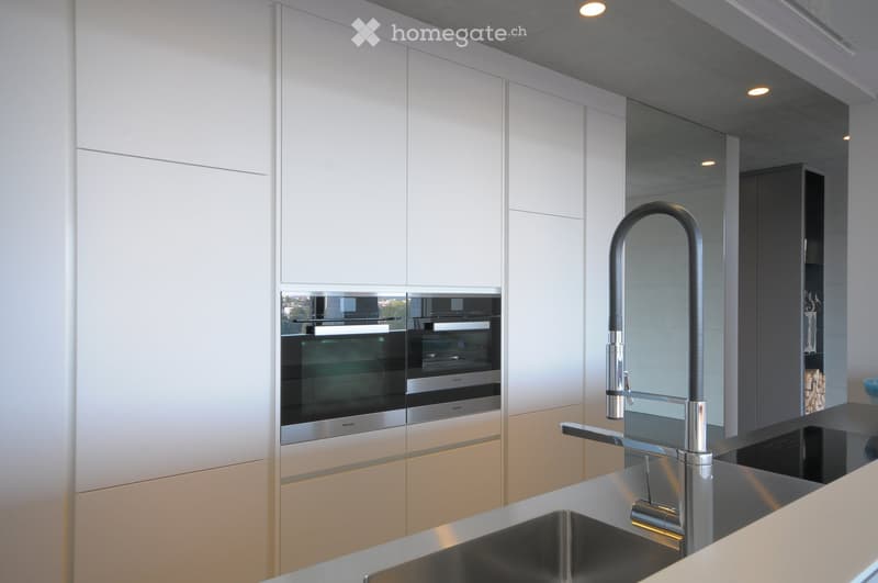 Modern kitchen with white cabinets, stainless steel appliances, and a sleek faucet over a sink.