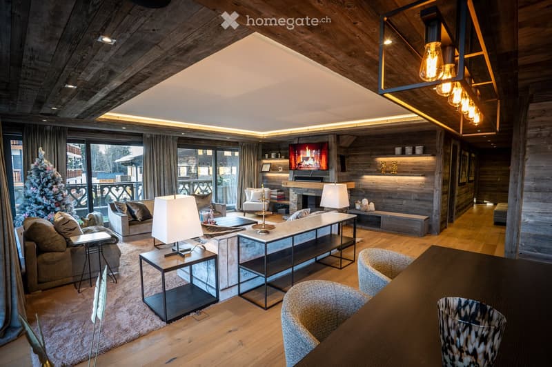 Modern living room with wooden beams, large windows, a fireplace, and a TV. Features a sofa, coffee table, armchairs, and table lamps.