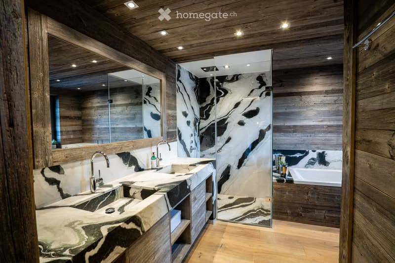 Modern bathroom with wooden walls and ceiling, marble sink, glass shower enclosure, and bathtub.