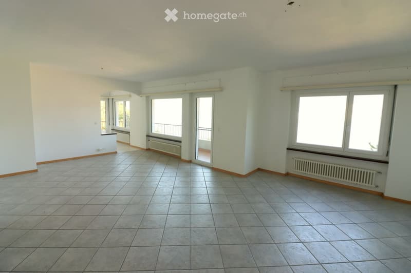Empty room with tiled floor, white walls, large windows, and a sliding glass door leading to a balcony.