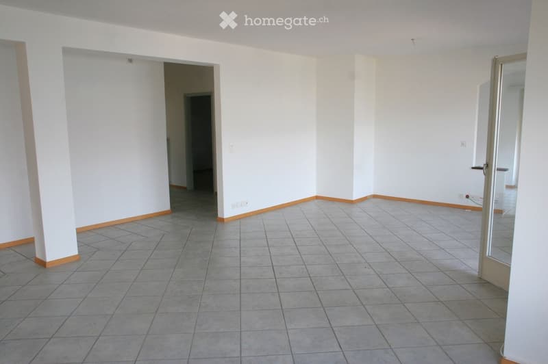 Empty room with white walls, tiled floor, and wooden baseboards. Features a doorway leading to another room and a glass door with a metal frame.