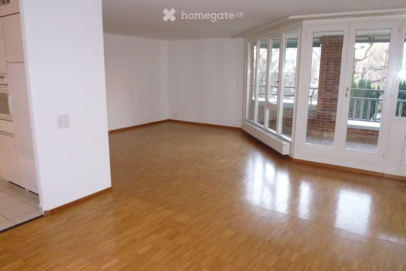 Empty room with polished hardwood flooring, white walls, and large glass sliding doors leading to an outdoor area.