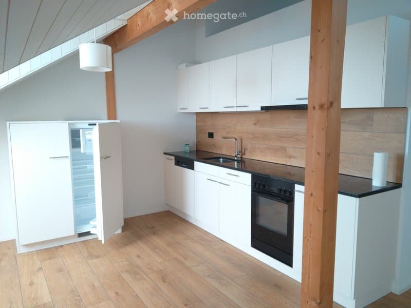 Modern kitchen with white cabinets, wooden accents, and stainless steel appliances including a refrigerator, sink, oven, and dishwasher.