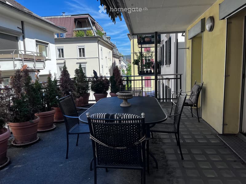 Balcony with a round table, four chairs, and several potted plants.