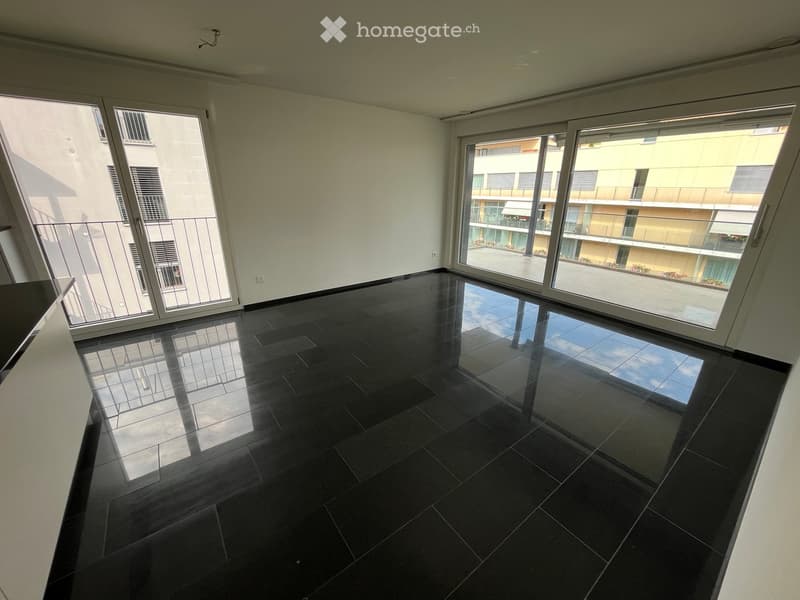 Empty room with dark tiled floor and large sliding glass doors leading to a balcony.