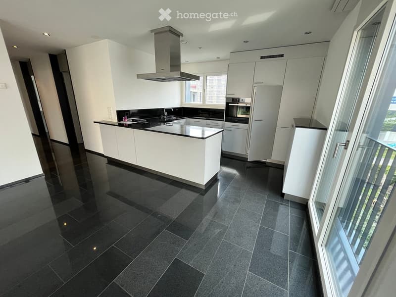Modern kitchen with white cabinets, black countertops, stainless steel appliances, and a large island.