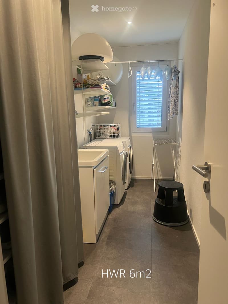 Laundry room with a washing machine, dryer, shelf, and a small window with blinds.