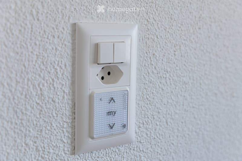 A modern electrical outlet with two switches and a USB port, mounted on a textured white wall.