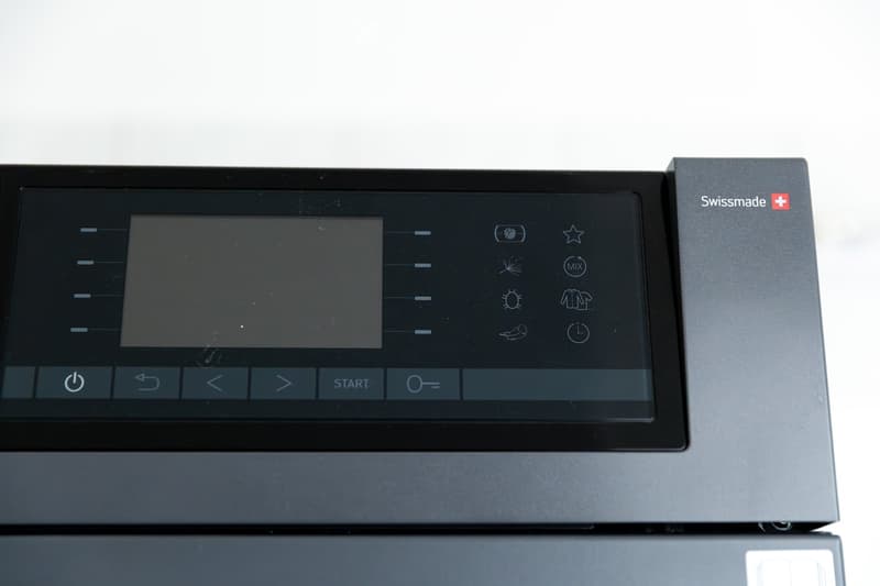 A modern control panel with a touchscreen display and various icons for settings and functions, featuring a sleek black design with the brand name 'Swissmade' visible.
