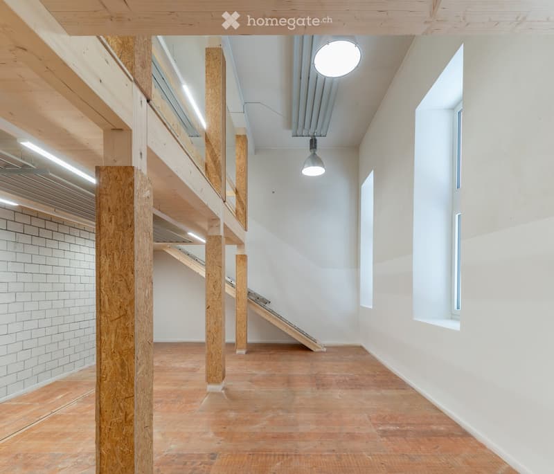 Modern hallway with wooden floors, exposed wooden beams, white walls, and a staircase leading to an upper level.