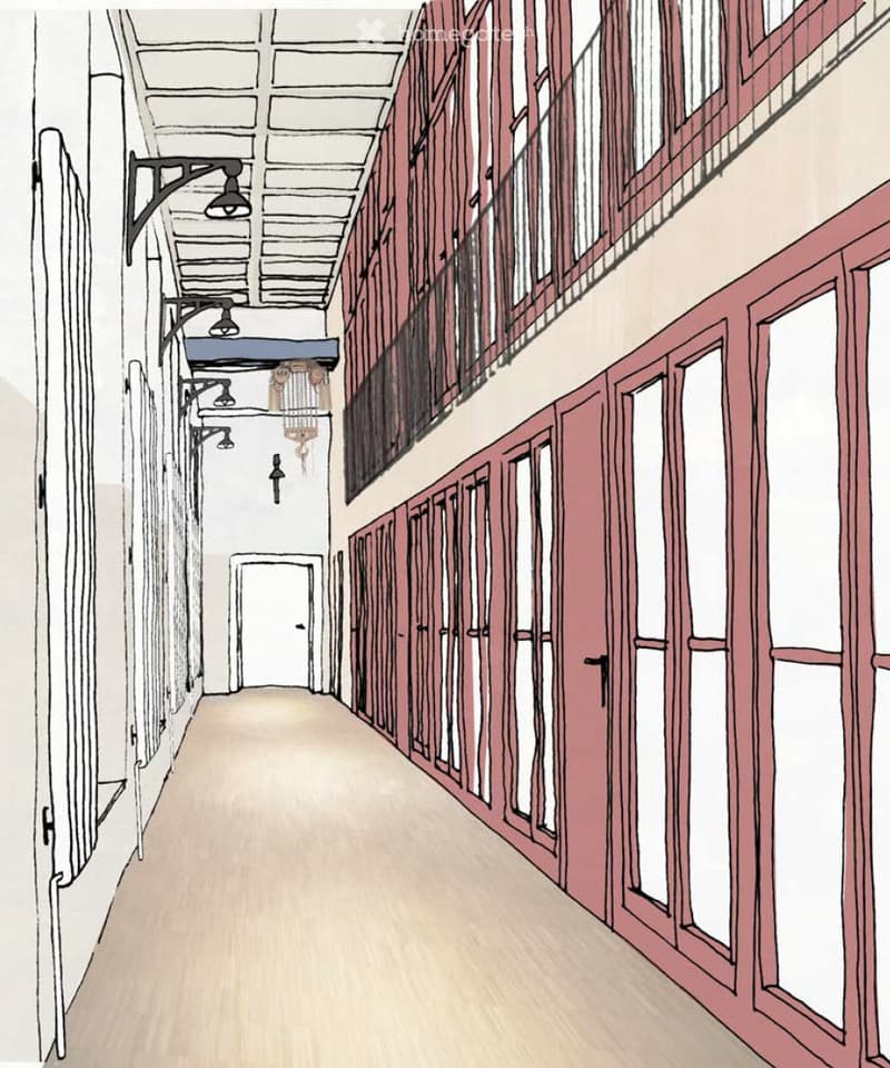 A long, narrow hallway with wooden flooring, exposed wooden beams on the ceiling, and several doors on both sides. The hallway features wall-mounted lighting fixtures and a chandelier hanging from the ceiling.