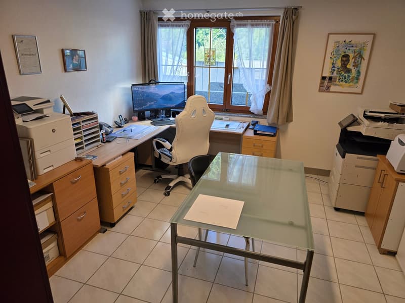 Office space with a large desk, ergonomic chair, computer screen, printer, and glass table.