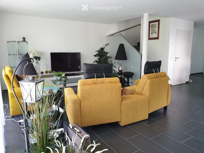 Modern living room with dark tiled flooring, yellow sofa, coffee table, TV, and decorative plants.