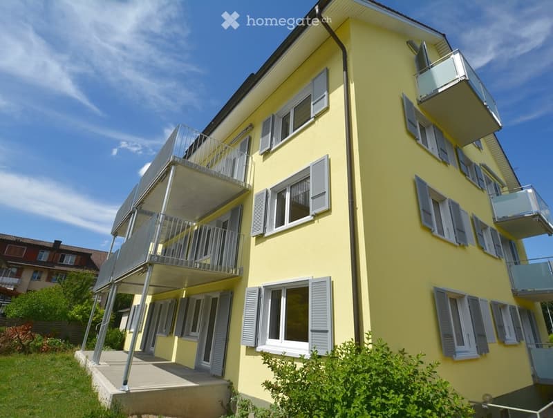 Four-story yellow building with multiple balconies and white shutters on windows.