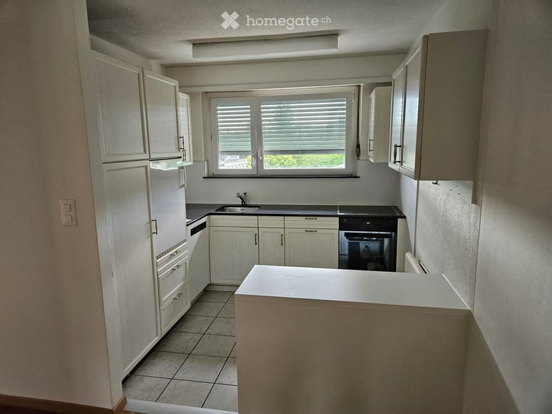 Modern kitchen with white cabinets, a central island, and built-in appliances including a refrigerator, oven, and sink.