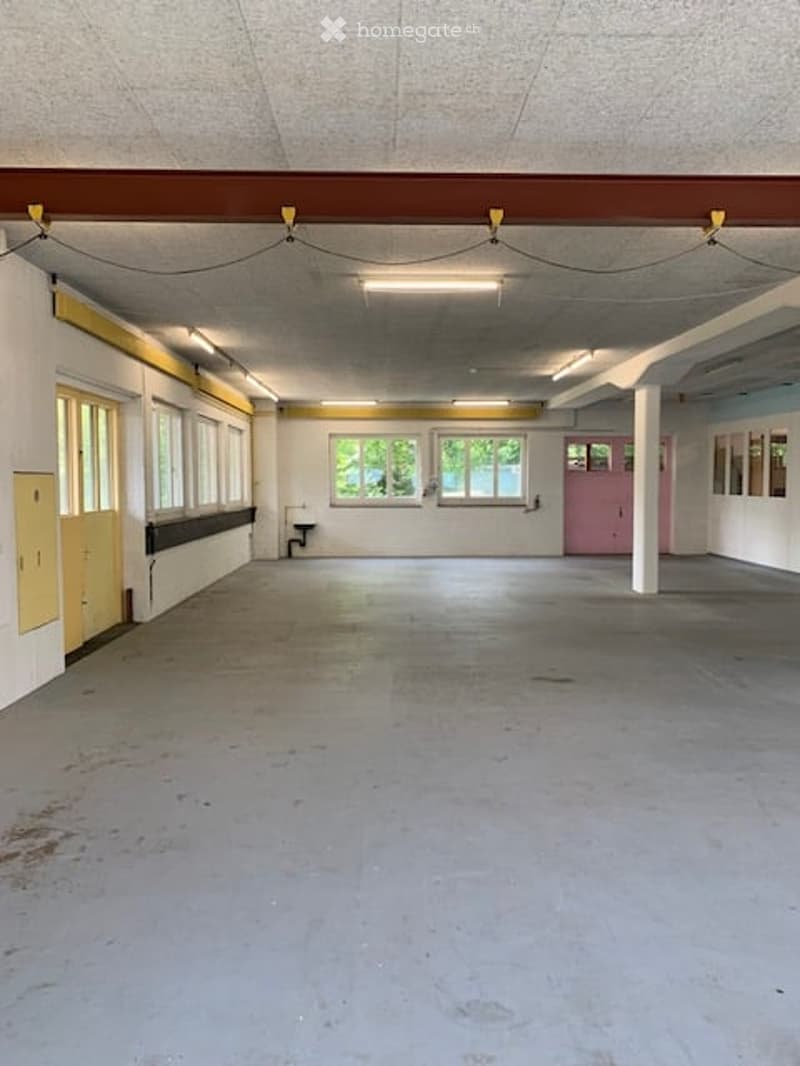 Empty room with bare walls, concrete floor, and large windows. No furniture or equipment present.
