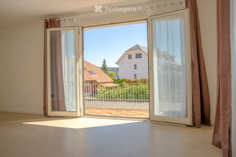 Empty room with large sliding glass doors leading to a balcony, beige walls, and light-colored carpeting.